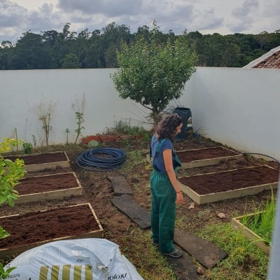 Jardim com canteiros de madeira e homem ao centro