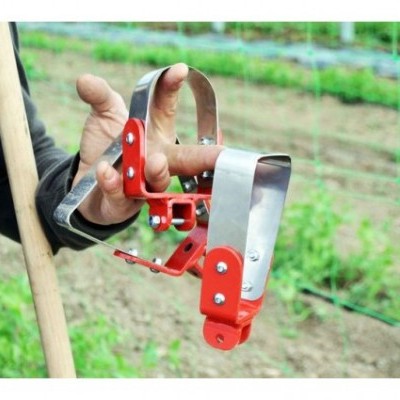 Dispositivo agrícola vermelho com presilhas metálicas em mão, campo de plantação ao fundo