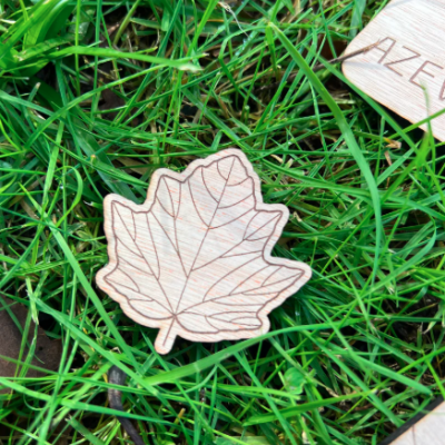 Peça de madeira em forma de folha de ácer sobre relva verde