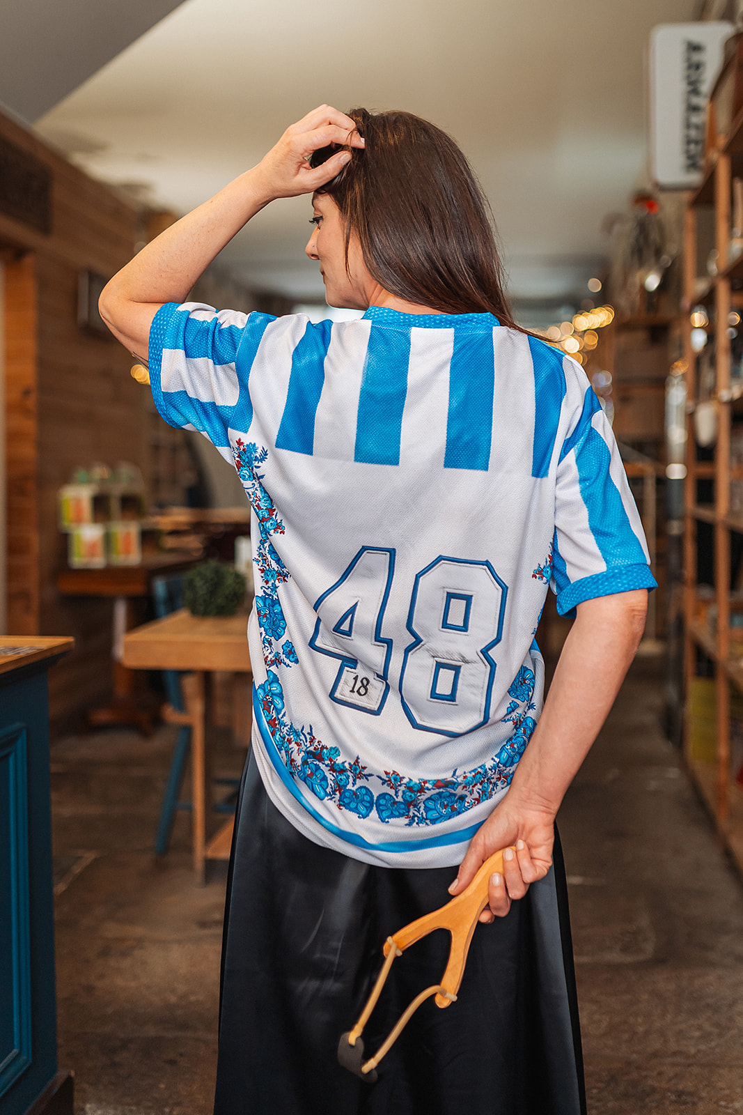 Camisola e Jogo Retro - Edição Azul & Branco Mulher de costas com t-shirt desportiva branca e azul com número 48 nas costas