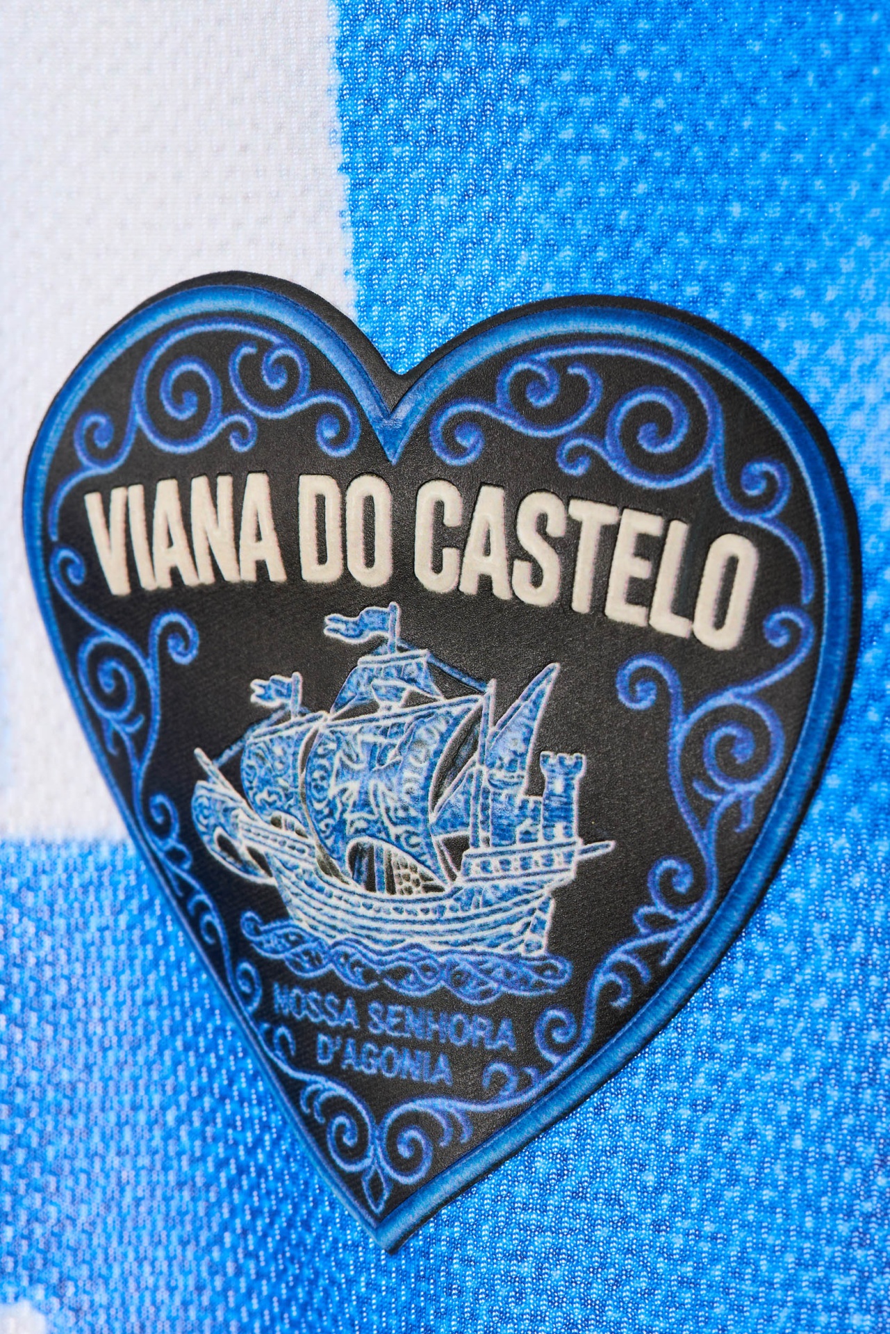 Camisola e Jogo Retro - Edição Azul & Branco Etiqueta em forma de coração azul escuro com texto Viana do Castelo sobre tecido azul e branco.