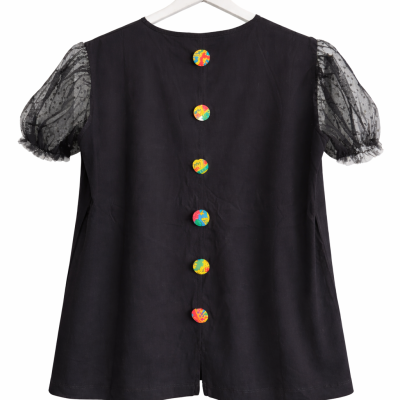Blusa preta com botões coloridos e mangas transparentes com bolinhas.