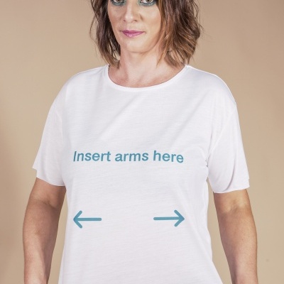 T-shirt branca com texto azul e setas usada por mulher com cabelo castanho e calças pretas