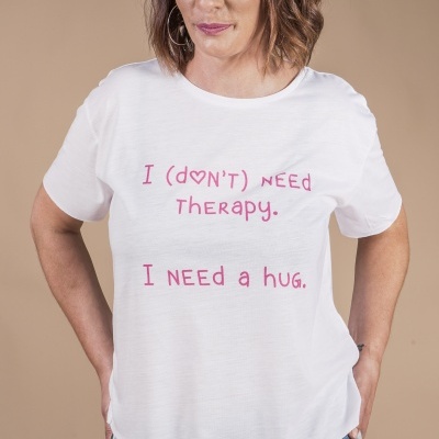 T-shirt branca com texto rosa e calças de ganga rasgadas em fundo bege