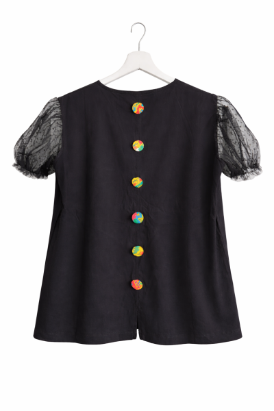 Blusa preta com botões coloridos e mangas transparentes com bolinhas.