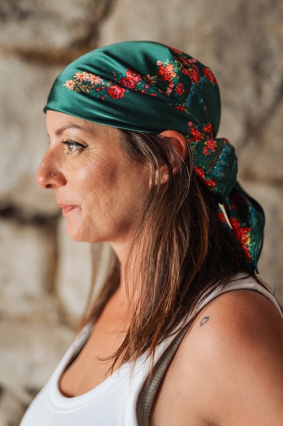 Lenço verde floral usado na cabeça por mulher de perfil com tatuagem ao ombro