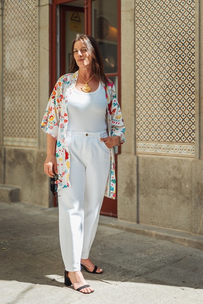 Mulher com roupa branca e kimono floral numa rua com azulejos