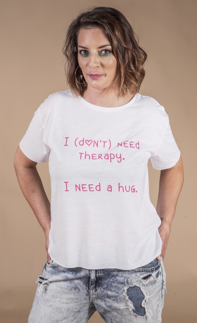 T-shirt branca com texto rosa e calças de ganga rasgadas em fundo bege