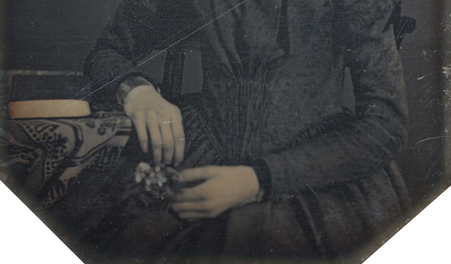 Mulher vestida de preto sentada a segurar flores com um livro ao lado