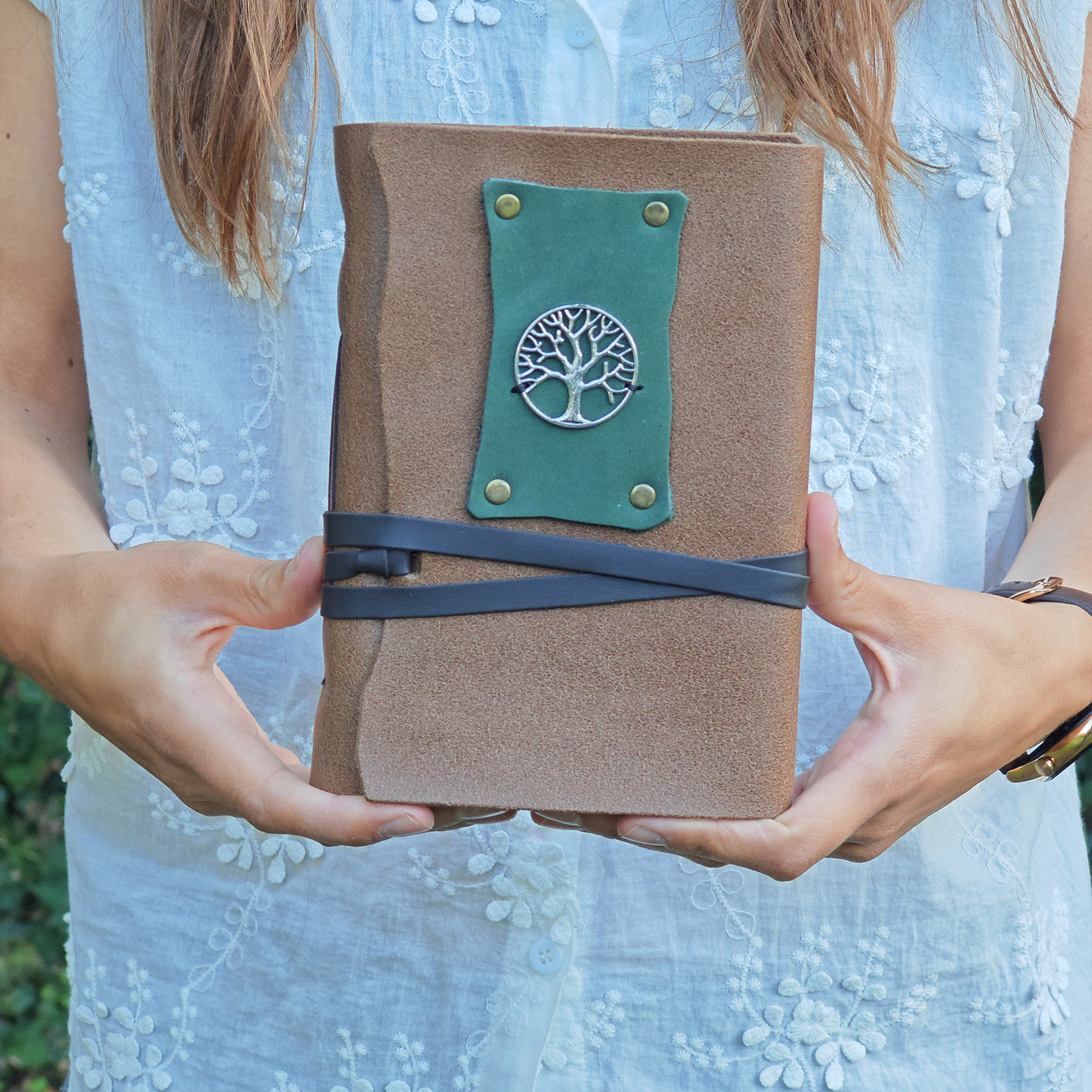 Caderno Árvore da Vida Caderno de capa em camurça castanha com faixa de couro verde e emblema de árvore