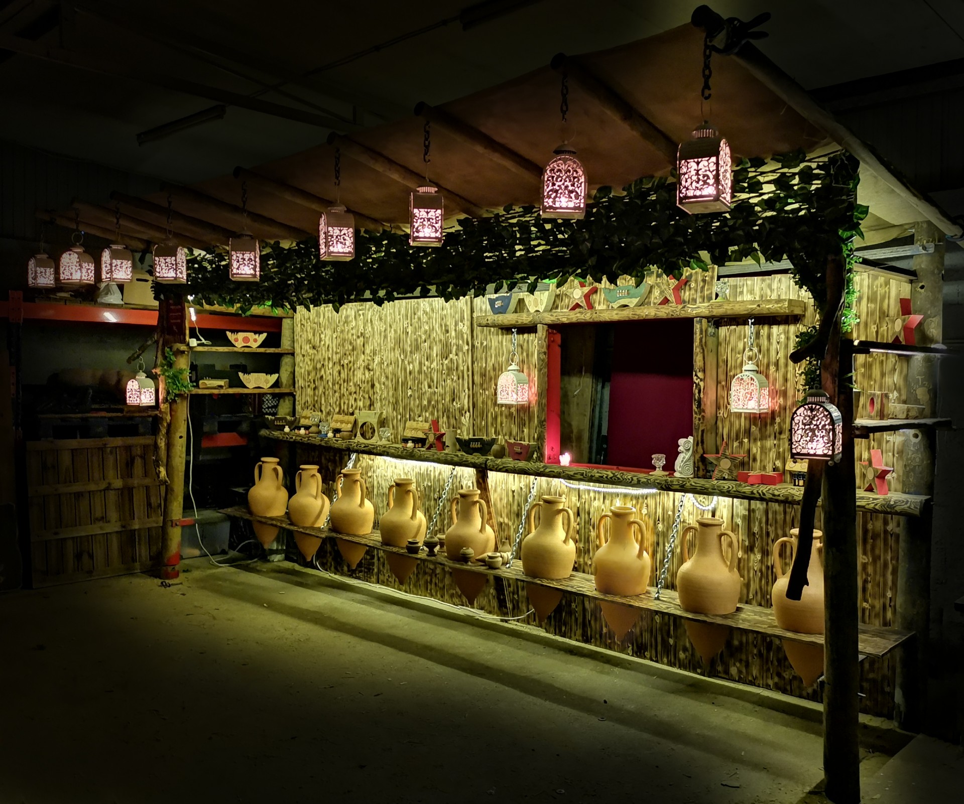 Banca de madeira rústica com jarros de cerâmica e luzes pendentes decorativas