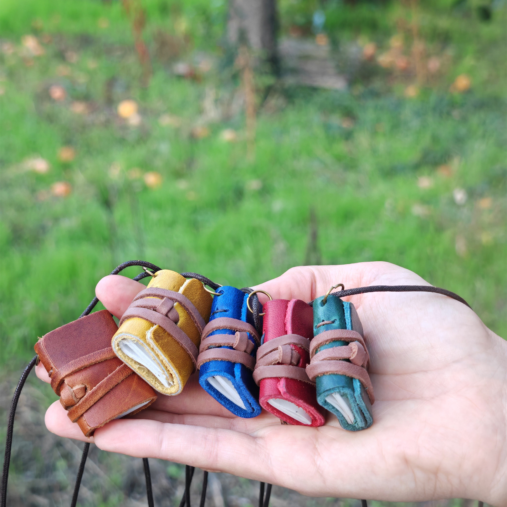 Caderno Miniatura Cinco mini cadernos com capa em couro colorido na mão ao ar livre