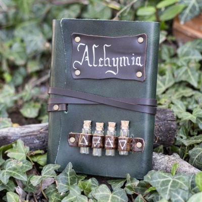Caderno em couro verde escuro com frascos de vidro e etiqueta 'Alchymia'