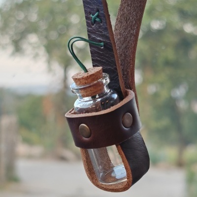 Frasco de vidro com rolha suspenso em alça de couro
