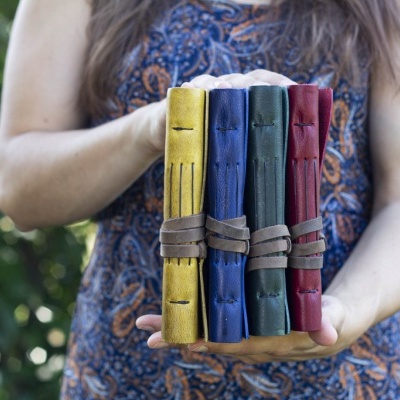 Quatro cadernos de pele coloridos a serem exibidos por uma pessoa ao ar livre