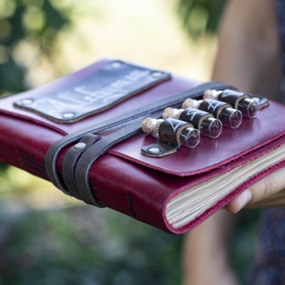 agenda com capa de couro vermelha e frascos de vidro presos com tiras de couro