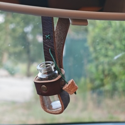 Frasco de vidro suspenso por correia de couro castanho no espelho retrovisor do carro