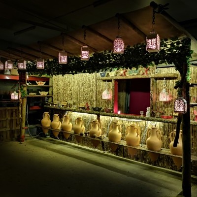 Banca de madeira rústica com jarros de cerâmica e luzes pendentes decorativas