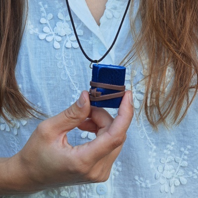 Colar com pendente em forma de mini livro azul escuro com correia de couro castanha