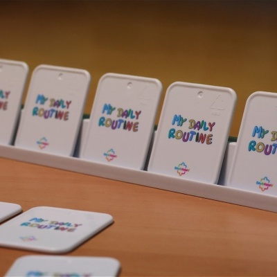 White plastic cards with MY DAILY ROUTINE text in a white stand on a wood surface