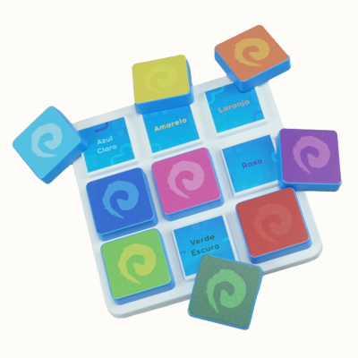Colorful square matching game pieces with spiral design on white tray with blue labeled slots in Portuguese.