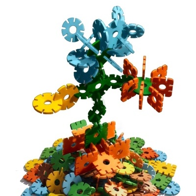 Colorful plastic gear and flower-shaped interlocking construction toy pieces assembled and scattered on white background