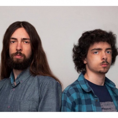 Dois homens jovens de camisa azul em fundo cinza