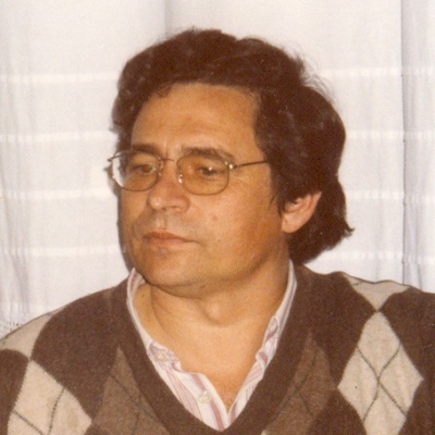 Homem de óculos e camisola castanha com padrão de losangos