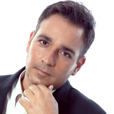 Homem com blazer preto e camisa branca num fundo branco