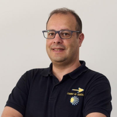 Homem com óculos e polo preta bordada do Caminho de Santiago