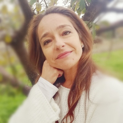 Mulher com camisola branca junto a uma árvore com frutos amarelos ao ar livre