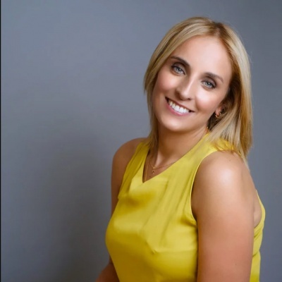 Mulher com blusa amarela sorrindo com fundo cinzento