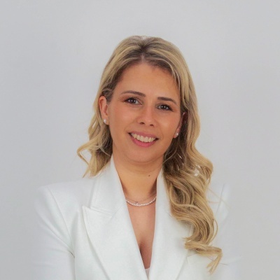 Mulher loira com vestido branco e colar em fundo branco