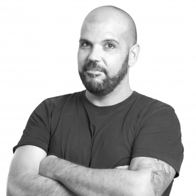 Homem com camisola preta e braços cruzados em fundo branco