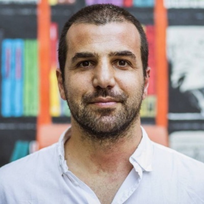 Homem de camisa branca com estante de livros ao fundo