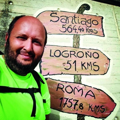 Placa de madeira pintada na parede com direções e distâncias e homem com camiseta verde