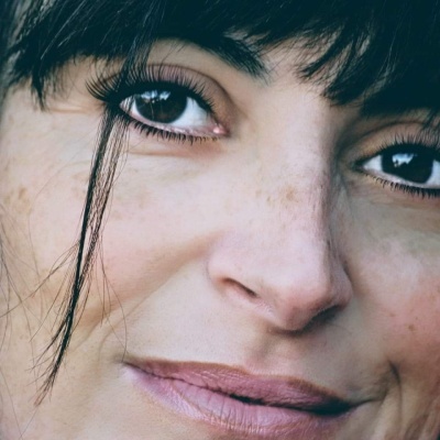 Close-up do rosto com olhos castanhos e cabelo preto com franjas.