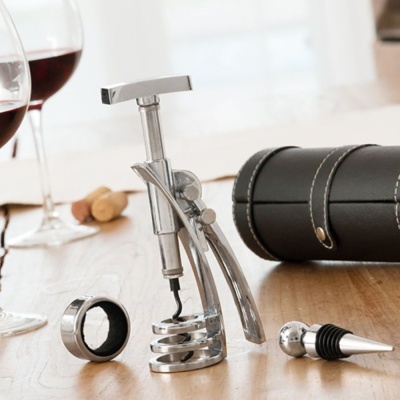 Conjunto de acessórios para vinho em metal prateado com estojo preto sobre mesa de madeira