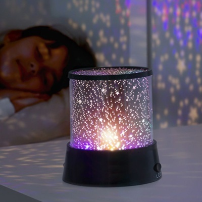 Projetor de luz LED cilíndrico preto com padrão de estrelas a projetar luz sobre mesa branca