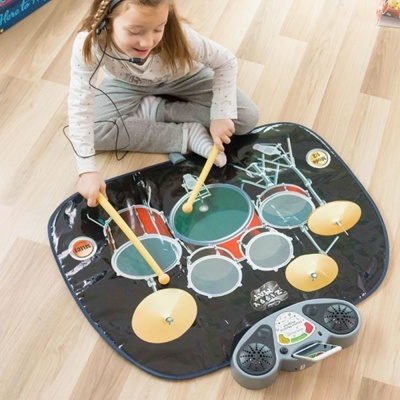Criança usando tapete musical de bateria colorido em chão de madeira