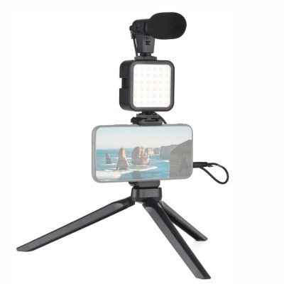 Tripé preto com microfone, luz LED e smartphone com imagem de paisagem