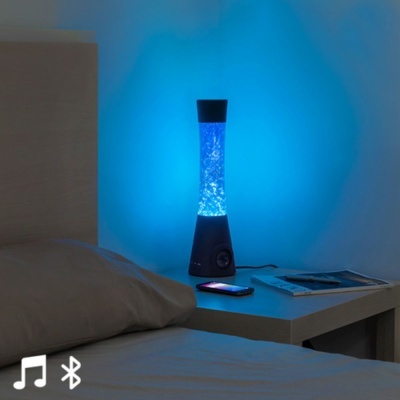 Candeeiro lava lamp azul numa mesa junto a uma cama