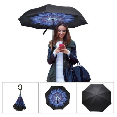 Guarda-chuva invertido preto com padrão floral azul no interior, segurado por mulher com casaco verde-escuro e mala preta