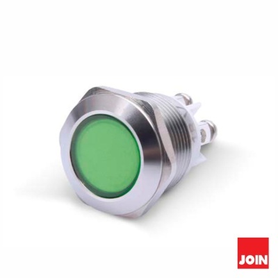 Botão de pressão metálico com superfície verde e conexões elétricas.