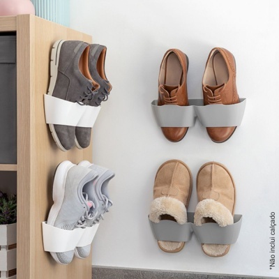 Três pares de calçado montados na parede com suportes plásticos de cor branca e cinzenta
