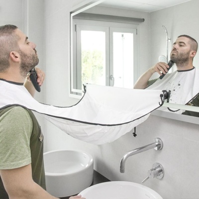Homem a barbear-se usando capa para apanhar pêlos de barba na casa de banho