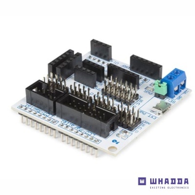 Placa eletrónica branca com conectores pretos, pinos dourados e elementos azul e verde.