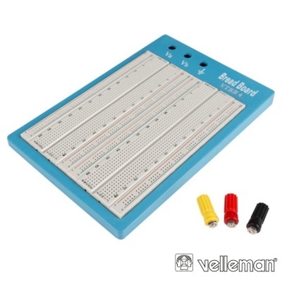 Breadboard azul com superfície branca perfurada e três pinos de ligação coloridos