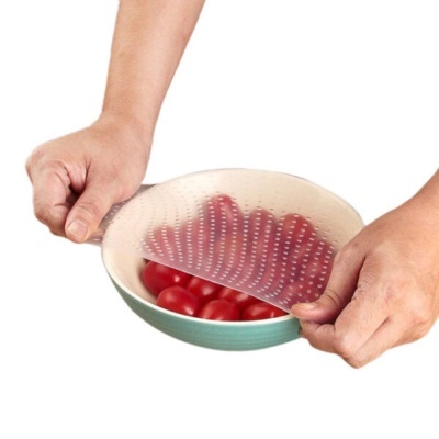 Tampa elástica transparente sobre tigela verde e branca com tomates-cereja vermelhos