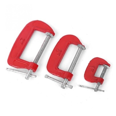 Três grampos C vermelhos de tamanhos diferentes sobre fundo branco